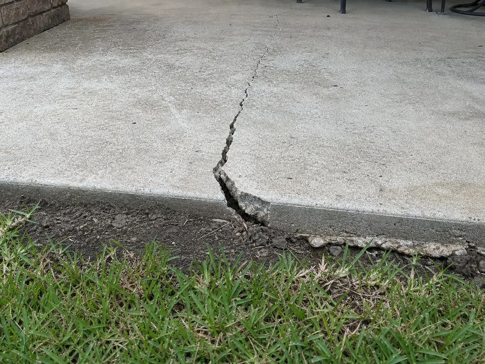 Cracked and settled concrete patio slab showing clay soil movement damage