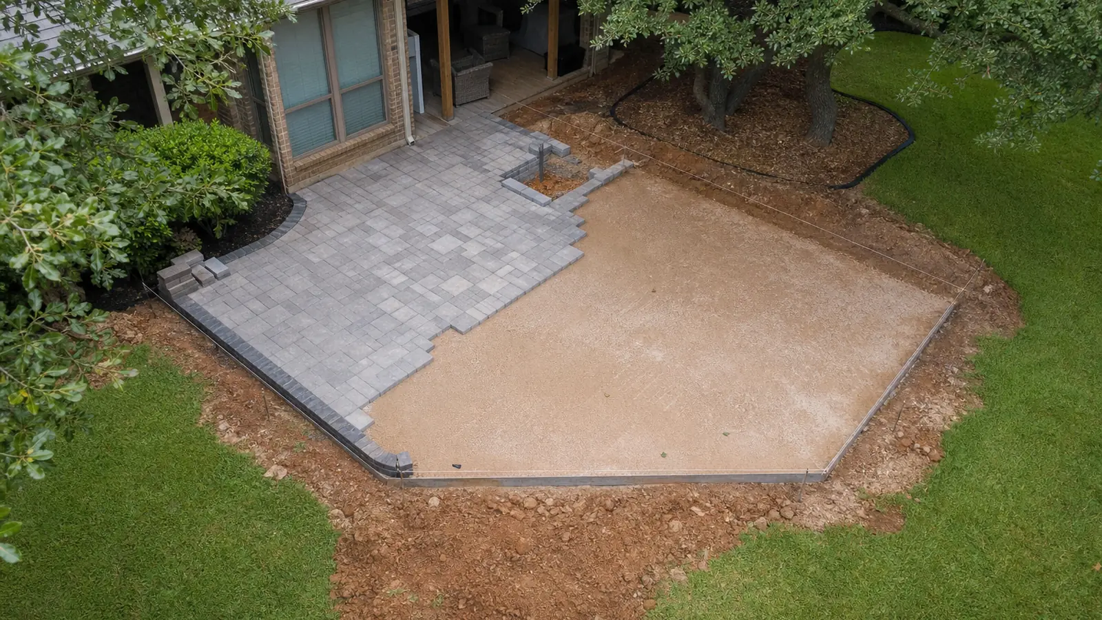 Paver patio mid-build in Keller TX with compacted base exposed beside finished pavers