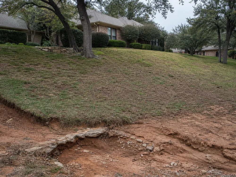 Failing retaining wall bulging outward with soil washing through open joints